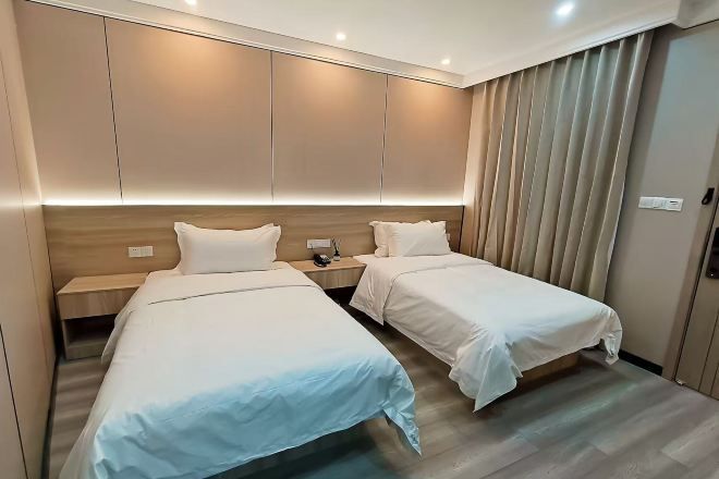 Una habitación de hotel con dos camas, un cabecero de madera, una mesita de noche y una cortina.