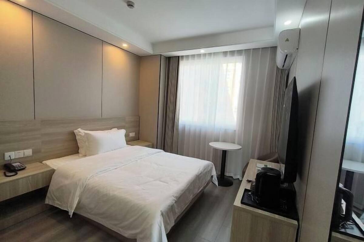 Ein Hotelzimmer mit Bett, Nachttisch, Fernseher und einem kleinen Tisch mit Kaffeemaschine.