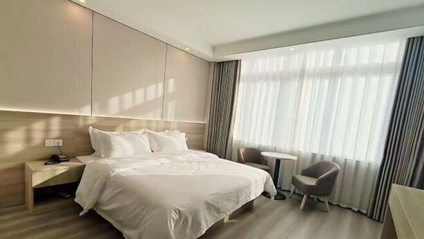 Una camera d'albergo moderna con un letto grande, un comodino, una sedia e un tavolino.