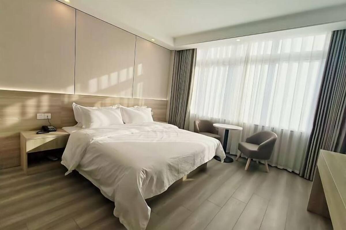 Ein modernes Hotelzimmer mit einem großen Bett, Nachttisch, Stuhl und einem kleinen Tisch.