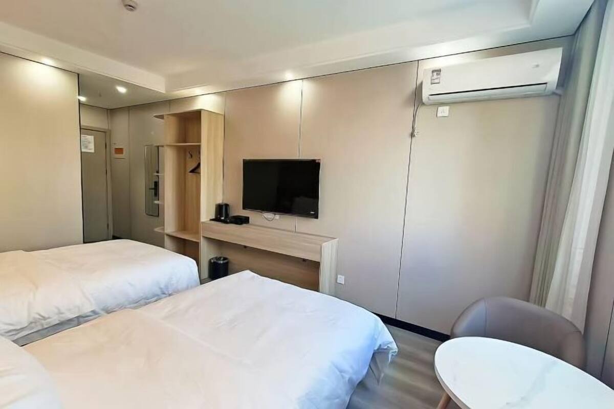 Ein Hotelzimmer mit zwei Betten, einem Fernseher, einem Schreibtisch und einem Stuhl.