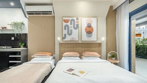 Moderni hotellihuone, jossa on sänky, yöpöydät, työpöytä ja taideteoksia seinällä.