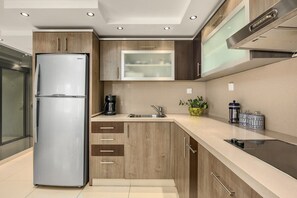 Una cocina moderna con refrigerador empotrado, cafetera y pileta.