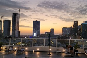 A rooftop terrace with lounge chairs and a city skyline at sunset. - DTLA Elegance & Style (1 bdrm, Free Parking, Pool) (Los Angeles)
