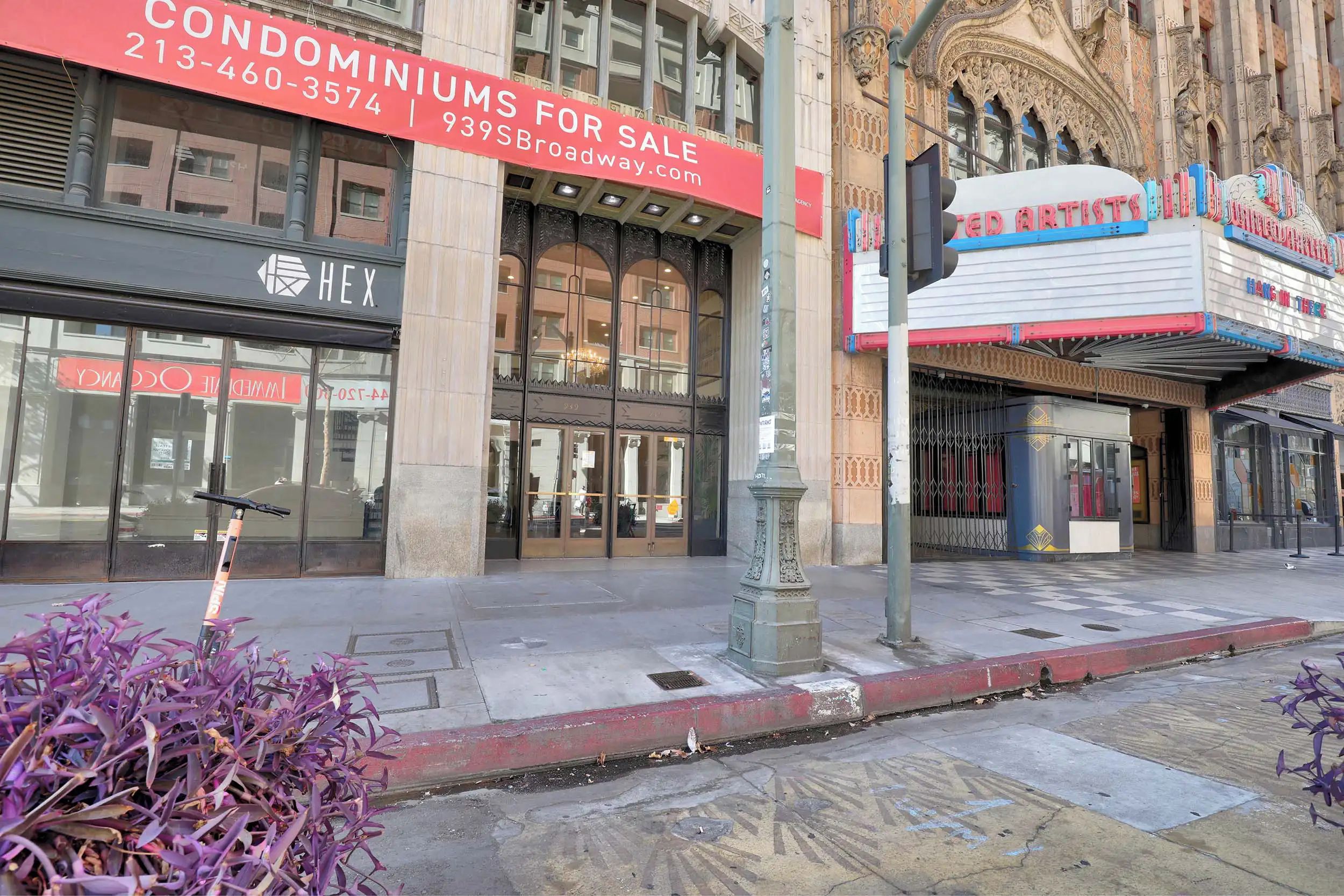 A building with a sign for condominiums for sale and a theater named 'RED ARTISTS'.