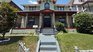 A two-story house with a stone facade, a black front door, and a small porch with a railing.
