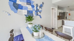 A dining area with a table set for two, a potted plant, and a wall map of the United States. - Swim & Unwind: Pet-Friendly Home in Spring! (Spring)