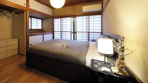 A bedroom with a bed, bedside table, lamp, and a window with a view.