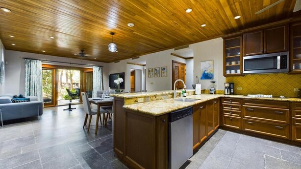 A spacious kitchen with wooden cabinets, a granite countertop, and a built-in dishwasher. - Tropical Retreat - 3 BDR/2 Bath condo, 2 min. walk to the Pacific Ocean. (Tamarindo)