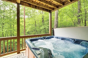 Un jacuzzi con cubierta de madera y vista a un bosque.