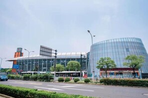 A modern building with a curved glass facade, a bus stop, and a clear sky. - Cloud Dream Inn (Shanghai South Railway Station Xuhui District Central Hospital) (Shanghai)