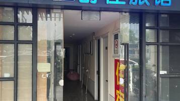 A hotel entrance with a glass door, a sign above the door, and a corridor leading inside.