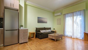 Una sala de estar con sofá, mesa de centro y refrigerador.