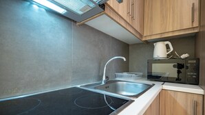 Una cocina moderna con cocina por inducción negra, pileta de acero inoxidable y muebles de madera.