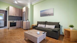 Una sala moderna con una mesa de centro de madera, un sofá gris y una cocina al fondo.