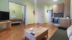 Una sala moderna con una televisión de pantalla plana, una mesa de centro de madera y una cama con cabecera.