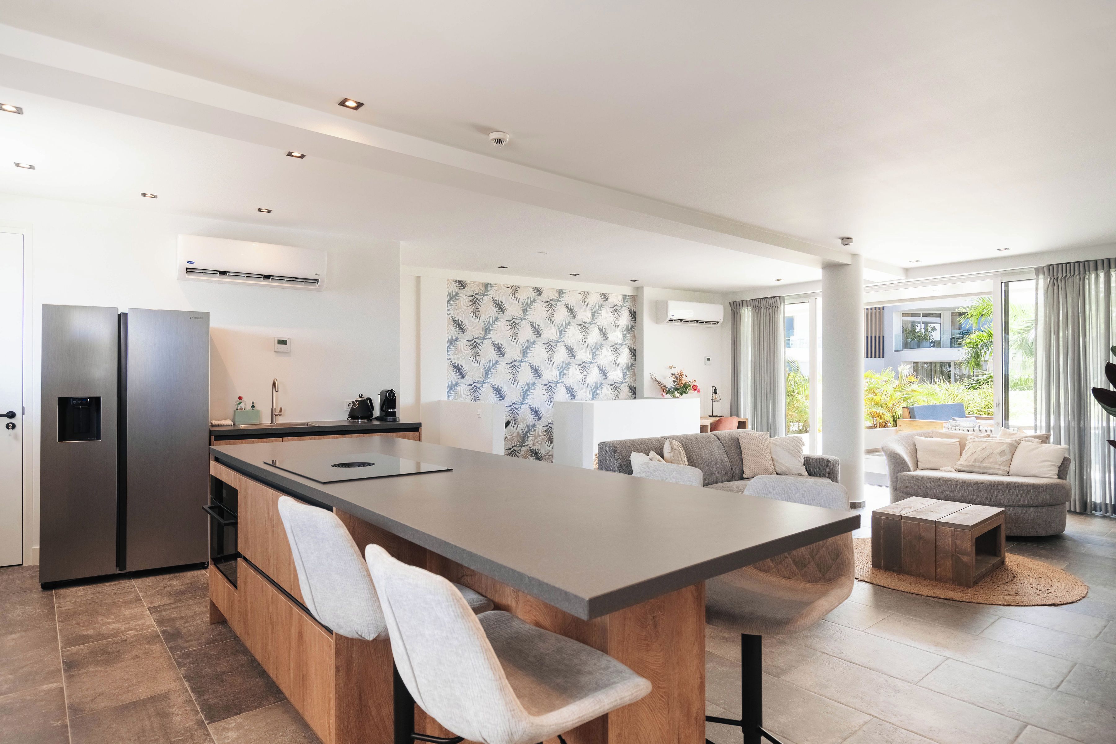 Una cocina moderna con una isla central, electrodomésticos integrados y una zona de comedor con sofá y mesa de centro.