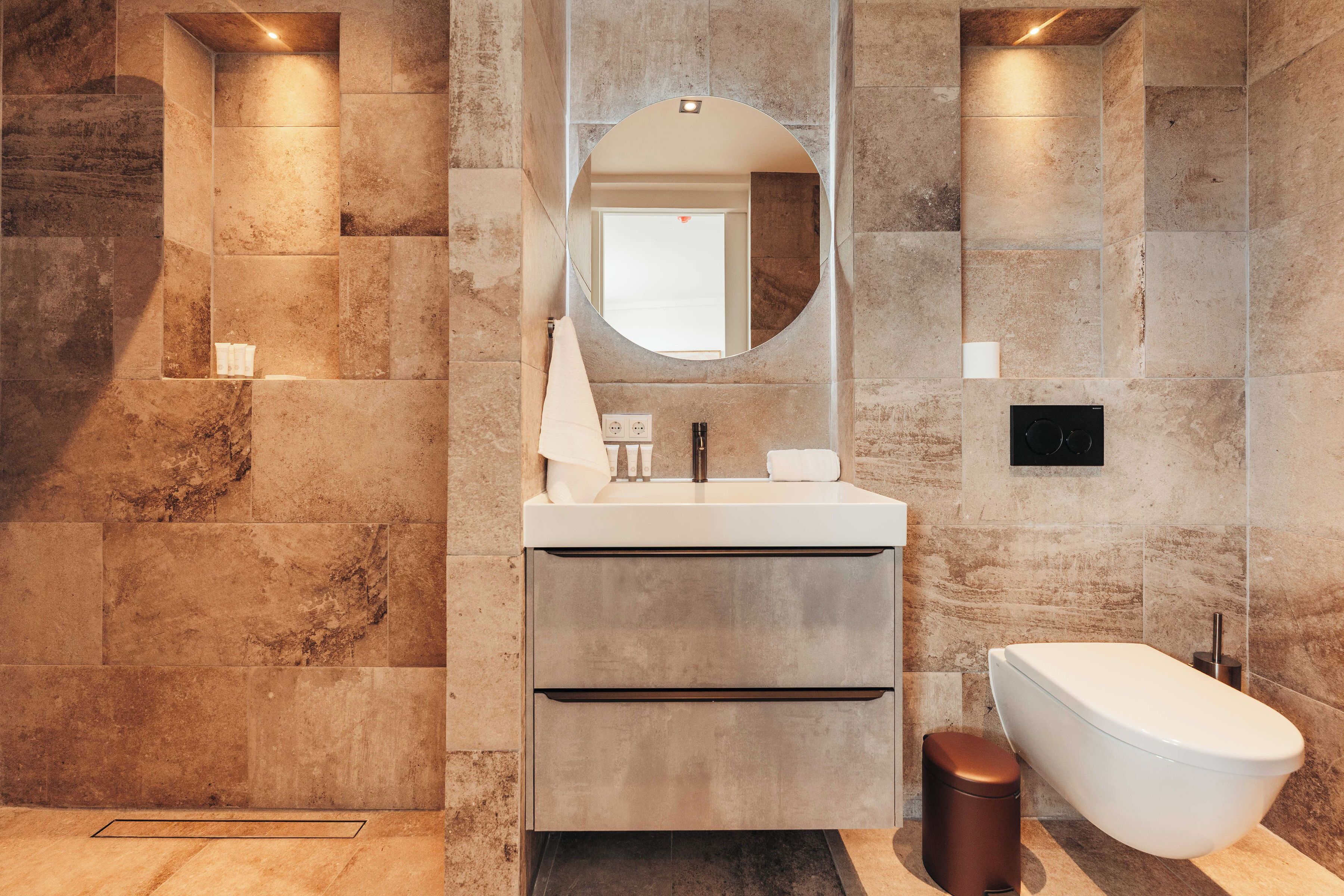 A modern bathroom with a large mirror, a white sink, and a freestanding bathtub.