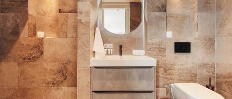 A modern bathroom with a large mirror, a white sink, and a freestanding bathtub.