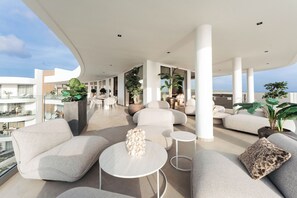 Un espace de vie moderne, à aire ouverte, avec des sièges confortables, une table basse et des plantes en pot.