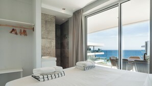 A modern hotel room with a large bed, a bathroom, and a balcony with a view of the sea. - ONE Mambo by Bocobay (Willemstad)