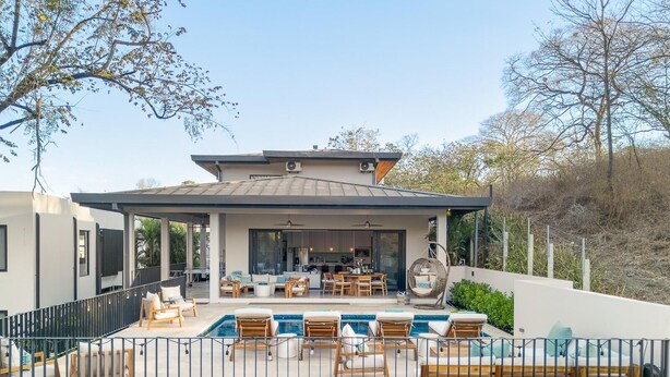 A modern outdoor living area with a pool, lounge chairs, and a covered patio. - 5BR Luxury Villa, Large Pool, 3-Min Walk to Beach, Concierge (Cabo Velas, Santa Cruz)