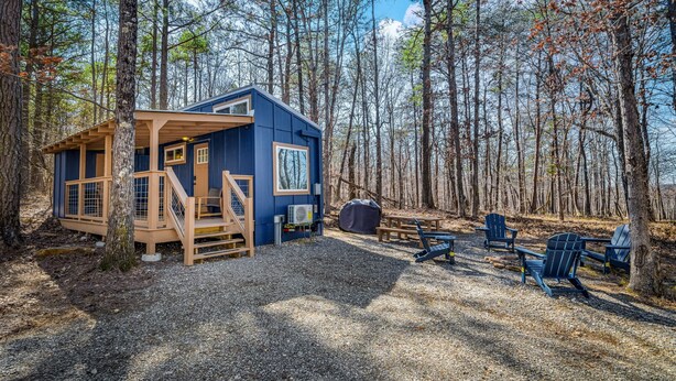 A small cabin with a wooden deck, a covered seating area, and outdoor furniture. - Tiny Cub House | Secluded Tiny House on 1.7 Acres, Mentone (Mentone)