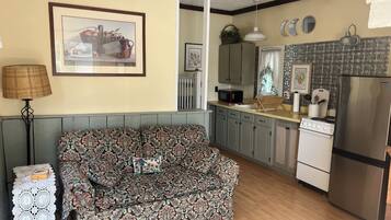 A cozy kitchen with a patterned sofa, a microwave, a refrigerator, and a sink.
