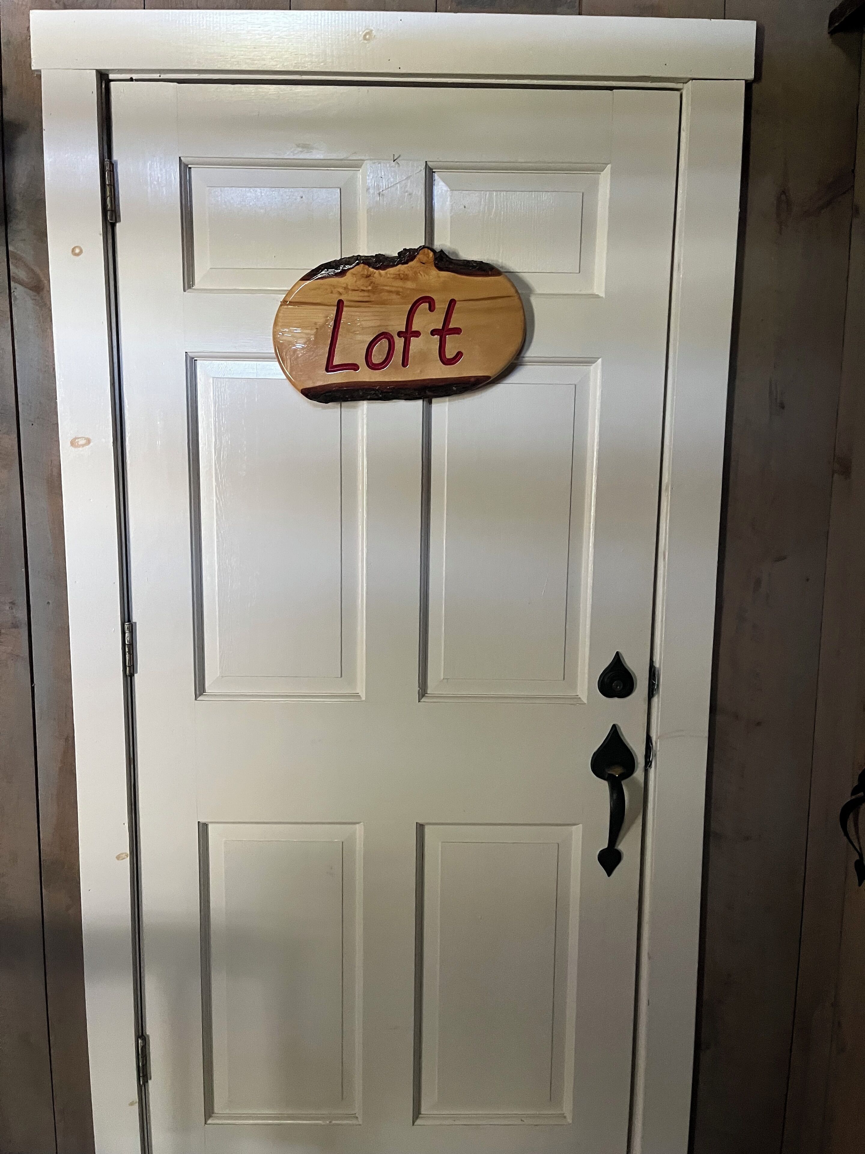 Eine weiße Tür mit einem Holzschild, auf dem 'Loft' steht.