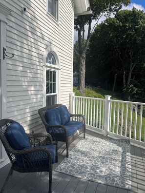 A porch with wicker chairs and a patterned rug.