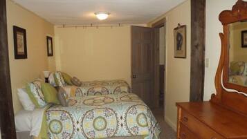 A bedroom with two beds, a wooden dresser, and a ceiling light.