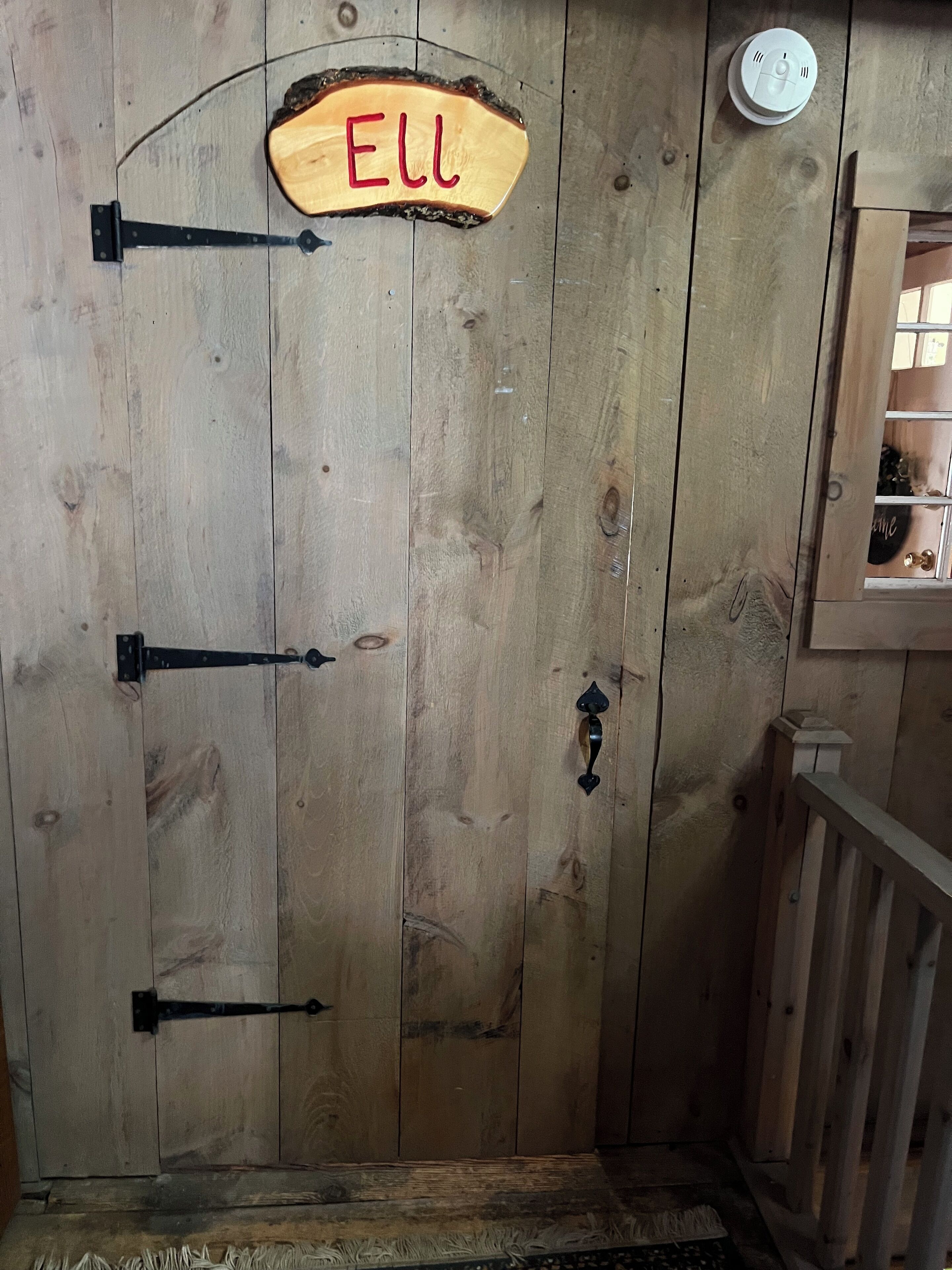 A wooden door with a sign reading "ELL" and a smoke detector above it.