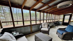 A covered outdoor seating area with wicker furniture, a bench, and a table. - Charming 2-bedroom cabin with AC just 3 miles from Sardis lake. (Sardis)