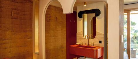Un baño moderno con un lavabo rojo, un espejo grande y una bañera.