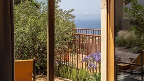 A room with large arched windows, a wooden deck, and a view of the sea. -  Hôtel Mylos - Cargèse (Cargèse)