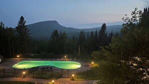 Une piscine entourée d’une clôture, avec une vue sur les montagnes en arrière-plan.