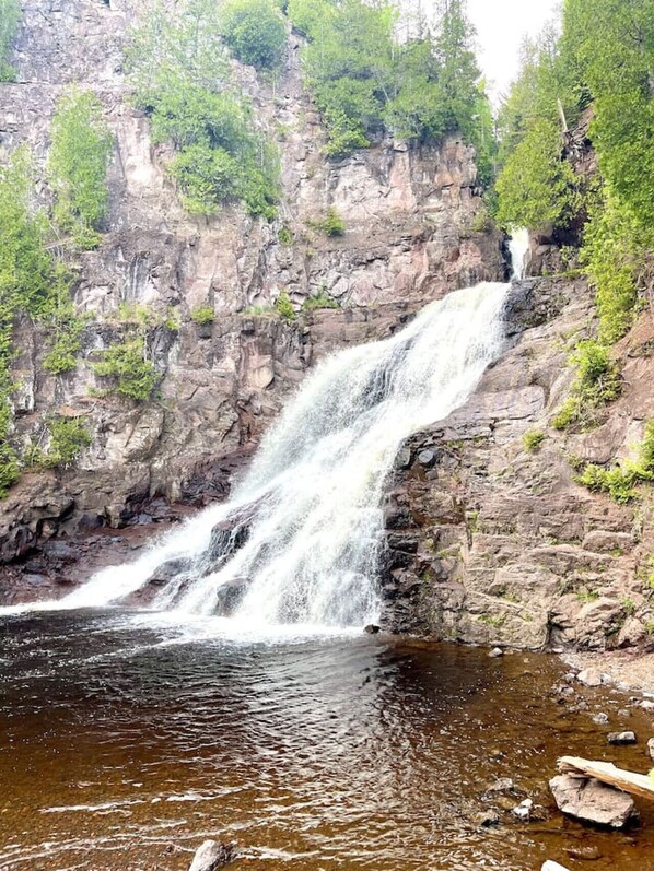 A waterfall cascading down a rocky cliff into a pool of water surrounded by greenery. - Lutsen Ski-In/Ski-Out | Lake View | Pet-Friendly (Lutsen)