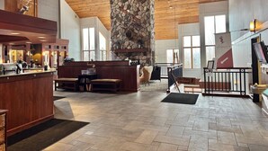 Un hall d’entrée spacieux avec une cheminée en pierre, un plafond en bois et un comptoir d’accueil.
