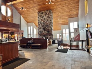A spacious lobby with a stone fireplace, wooden ceiling, and a reception desk. - Lutsen Ski-In/Ski-Out | Lake View | Pet-Friendly (Lutsen)