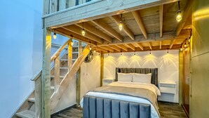 A bedroom with a wooden staircase, a bed with a headboard, and a fan. - Penthouse-PrivateJacuzzi-MarYSolCondo-3BR-Rosarito (Playas de Rosarito)