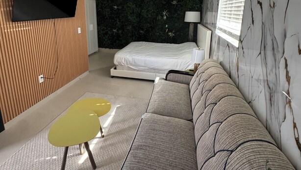 Ein modernes Schlafzimmer mit Bett, Sofa, Fernseher und kleinem Tisch.
