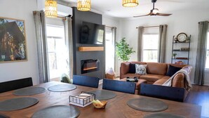 Ein modernes Wohnzimmer mit einem großen Holztisch, Ledersofas und einem Kamin.