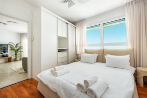 A hotel room with a large bed, a wardrobe, a bedside table, and a window with curtains.