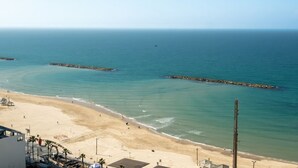 Une plage avec une eau d’un bleu limpide, un rivage sablonneux et quelques bâtiments visibles au premier plan.