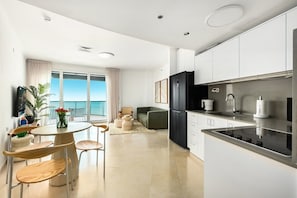 A modern kitchen with a black refrigerator, white cabinets, and a stainless steel stove.