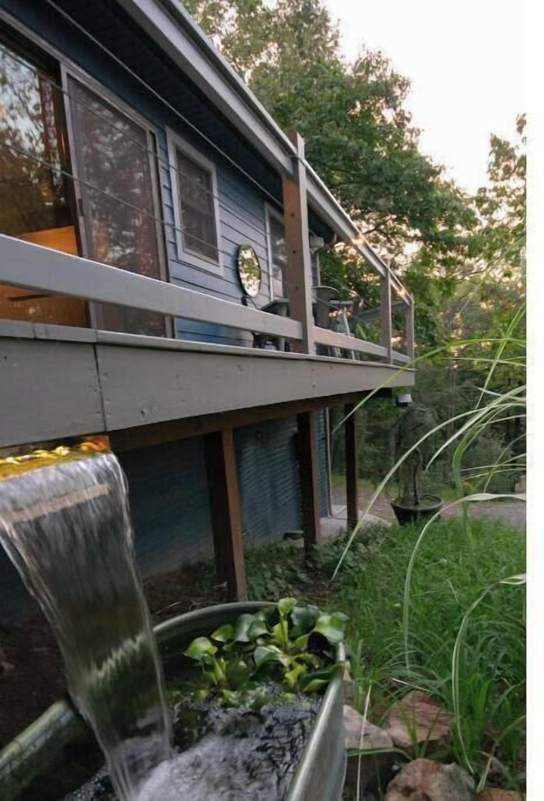 Une maison avec un balcon, un élément décoratif aquatique et un jardin.