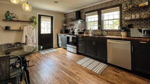 A modern kitchen with dark cabinetry, a central island, and a dining area with a glass table.