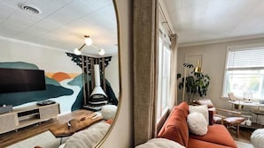 A modern living room with a large mirror, a sofa, a TV, and a fireplace.