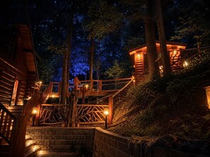 Une cabane en bois avec un escalier menant à une maison dans les arbres, le tout entouré de forêt.