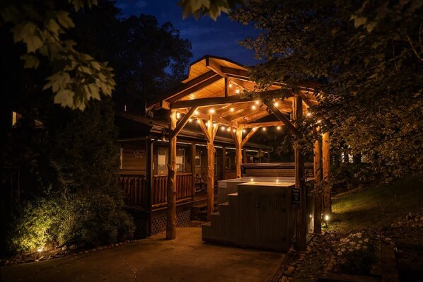 A wooden outdoor structure with a covered seating area and a hot tub.